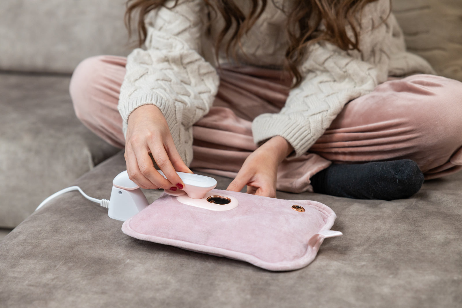 Vrouw op de bank die een roze Zenwave kruik elektrisch oplaadt